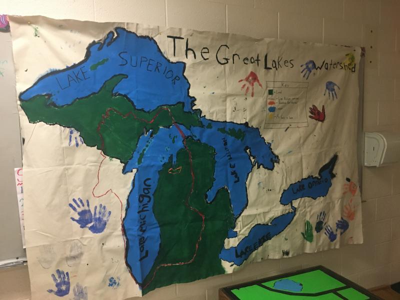 A floor map of the Great Lakes watershed painted and created by students at Forest Area Middle School SEEDS After School program. The Boardman River Watershed, in which their school is located, is outlined in orange. The Lake Michigan watershed is outlined in red. Photo courtesy of Joe Kreider.
